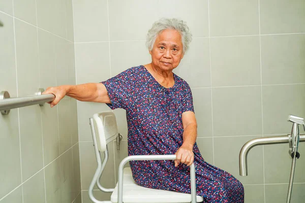 Asian elderly old woman patient use toilet support rail in bathroom, handrail safety grab bar, security in nursing hospital.