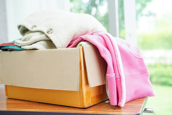 Clothes donations in cardboard box for volunteer.