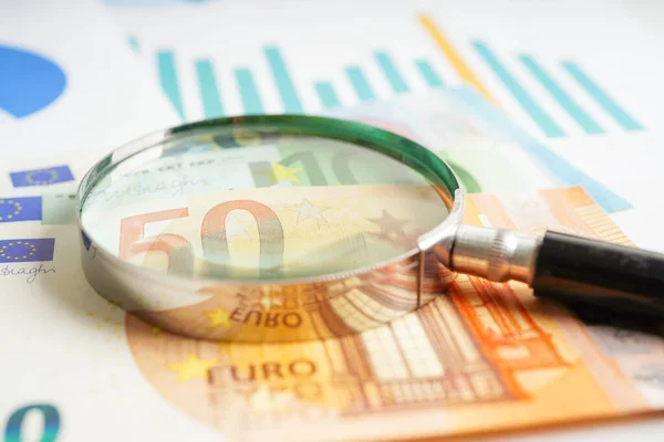 Magnifying glass on US dollar and EURO banknotes and graph, finance business trade concept.