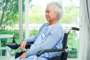 Parkta elektrikli sandalyede oturan Asyalı yaşlı kadın engelli hasta, tıbbi konsept..