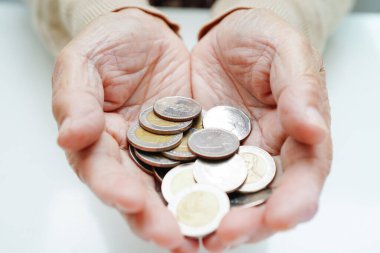  Retired elderly woman counting coins money and worry about monthly expenses and treatment fee payment.