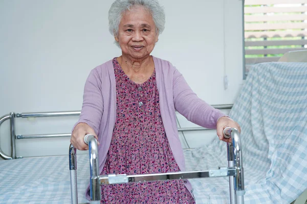 Asian elderly woman disability patient walk with walker in nursing hospital, medical concept.