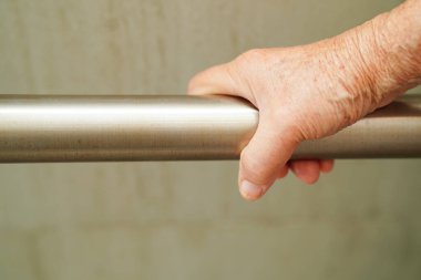 Asyalı yaşlı kadın hasta tuvalette tuvalet desteğini, tırabzan emniyet çubuğunu, hemşire hastanesinde güvenliği kullanıyor..