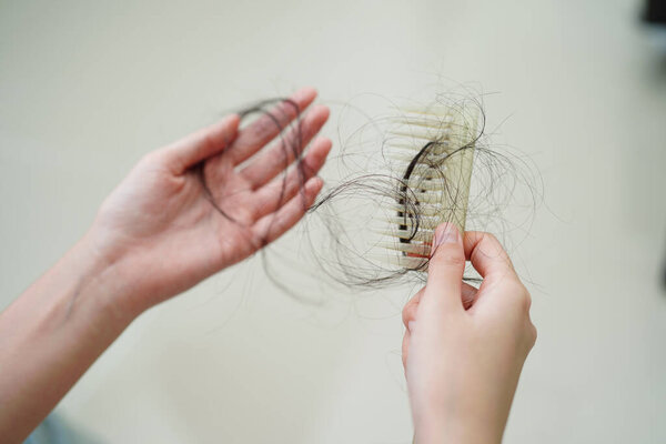 Asian woman have problem with long hair loss attach to comb brush.