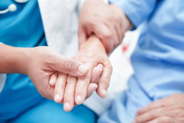 Doktor el ele tutuşuyor Asyalı yaşlı kadın hasta, hastanede yardım ve bakım.