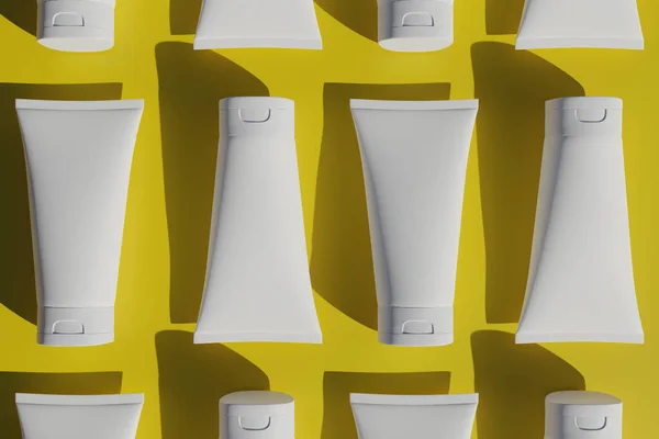 Sarı arka planda beyaz kozmetik tüpleri. Kozmetik için şablon, en az 3D biçim oluşturma.