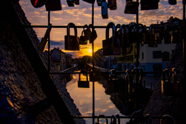 Gün batımında İtalya 'nın Milano kanalları. Rıhtımda gün batımında sıska bir şehir manzarası portakal ve ılık renklerle dolu.