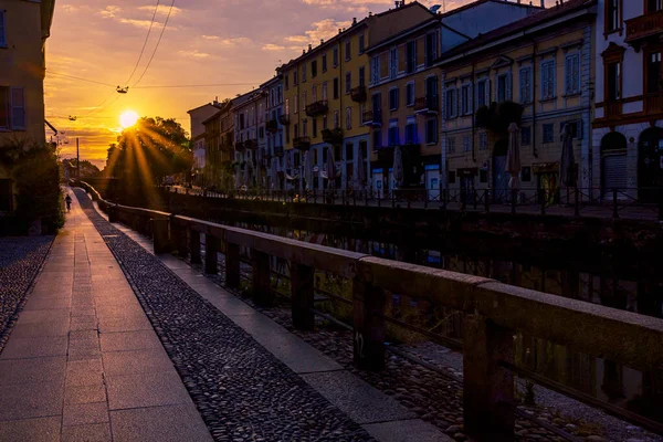 Gün batımında İtalya 'nın Milano kanalları. Rıhtımda gün batımında sıska bir şehir manzarası portakal ve ılık renklerle dolu.