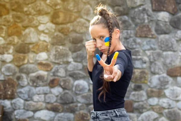 Kafkasyalı uzun saçlı, örgülü bir kız. Ukrayna bayrağının renkleriyle savaş ve barış jesti yaptı. Kopyalama alanı olan arkaplan Ukrayna ve Rusya savaş kavramı