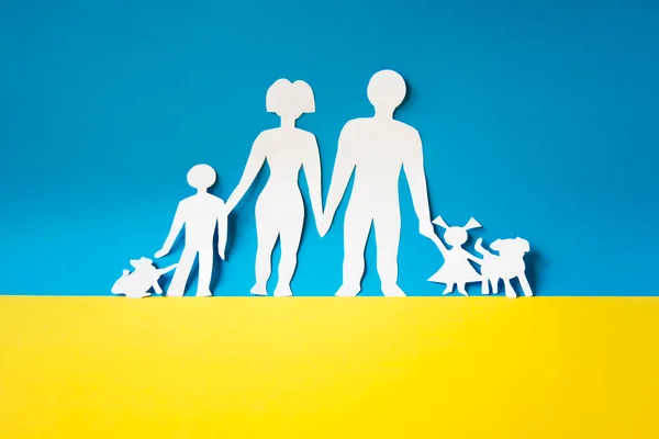 Ukrayna 'daki çatışmadan sivilleri kurtarmak için insan koridoru. Ukrayna bayrağında bir ailenin kağıt kesiği. Savaş mültecileri. aile kavramı.