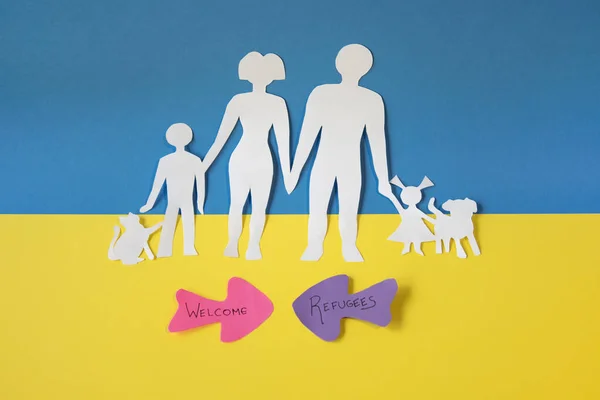 Göç sırasında ülkeyi terk eden Ukraynalı bir ailenin temsilcisi. Ukrayna bayrağının mavi ve sarı renklerinde kağıt kesiği.