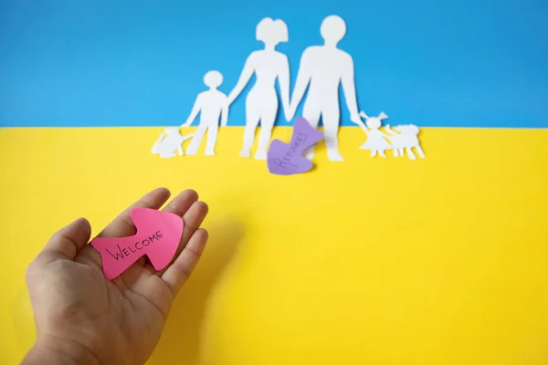 Beyaz bir kadının eli, Rusya 'ya karşı Ukrayna savaşından gelen mültecileri karşılıyor. Sivil nüfusun toplu göçü. kağıt kesimi.