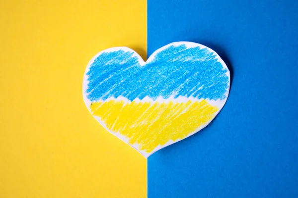 mavi arkaplan ve kağıttan kesilmiş bir kalp Ukrayna bayrağının renkleriyle destek göstermek için boyanmış..