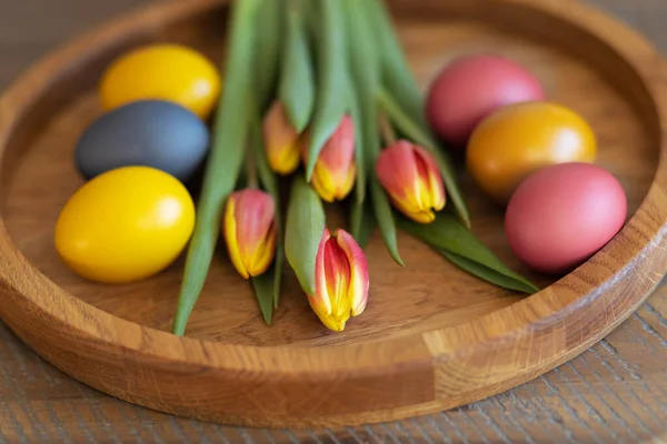 Šest jasných barevných vajec a tulipánů na dřevěném pozadí — Stock fotografie
