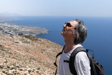 Bir adam deniz manzarası, Yunanistan ve Girit 'in arka planında sessizlikten zevk alır.