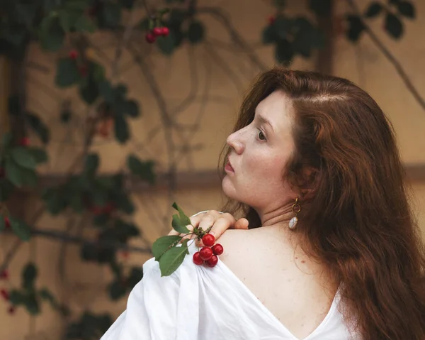 Portrait of a young woman with a sprig of cherry berries. High quality photo