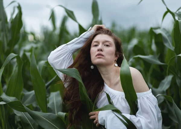 Portrait of a young woman on a background of corn with raised hands. High quality photo