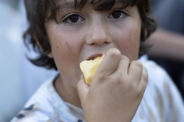 Brown-eyed cute boy eating an apple. High quality photo