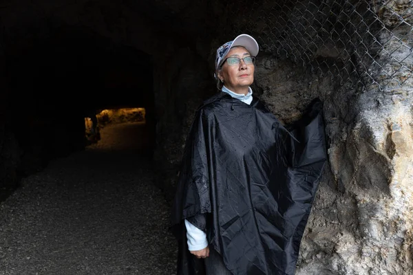 An adult woman stands at the entrance to an illuminated mountain tunnel, Austria, Salzburg. High quality photo