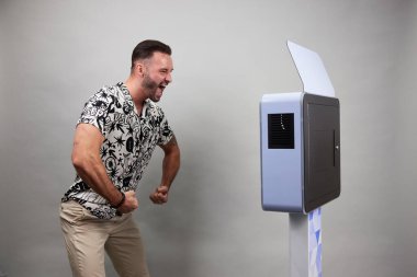 Erkek beyaz bir fotoğraf kabininin önünde poz veriyor.