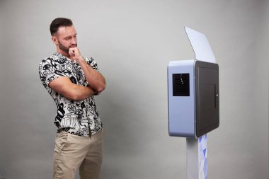 Erkek beyaz bir fotoğraf kabininin önünde poz veriyor.