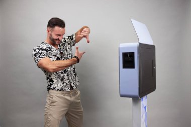 Erkek beyaz bir fotoğraf kabininin önünde poz veriyor.