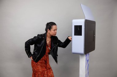 Beyaz bir fotoğraf kabininin önünde poz veren kadın.