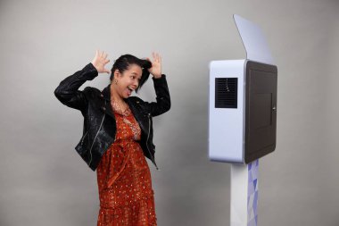 Beyaz bir fotoğraf kabininin önünde poz veren kadın.