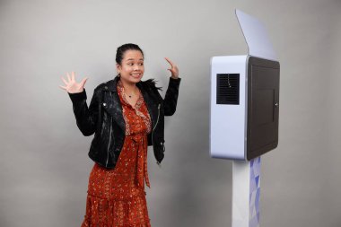 Beyaz bir fotoğraf kabininin önünde poz veren kadın.