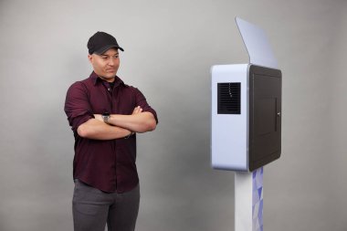 Erkek beyaz bir fotoğraf kabininin önünde poz veriyor.