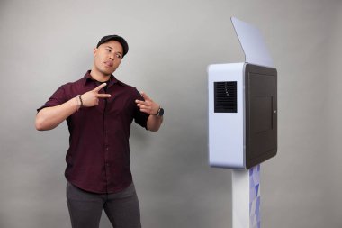 Erkek beyaz bir fotoğraf kabininin önünde poz veriyor.