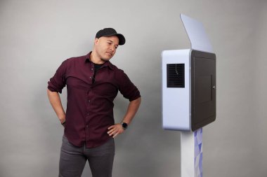 Erkek beyaz bir fotoğraf kabininin önünde poz veriyor.