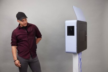 Erkek beyaz bir fotoğraf kabininin önünde poz veriyor.