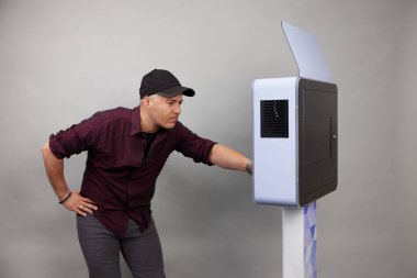 Erkek beyaz bir fotoğraf kabininin önünde poz veriyor.