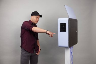 Erkek beyaz bir fotoğraf kabininin önünde poz veriyor.