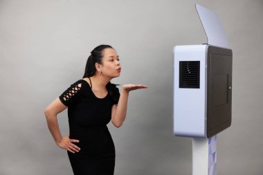 Beyaz bir fotoğraf kabininin önünde poz veren kadın.