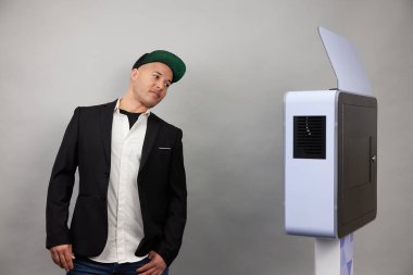 Erkek beyaz bir fotoğraf kabininin önünde poz veriyor.