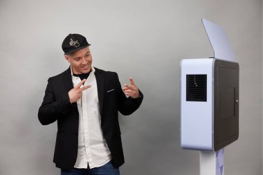 Erkek beyaz bir fotoğraf kabininin önünde poz veriyor.