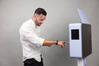 Erkek beyaz bir fotoğraf kabininin önünde poz veriyor.