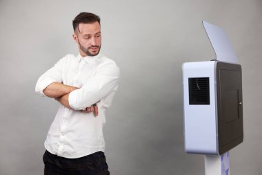 Erkek beyaz bir fotoğraf kabininin önünde poz veriyor.