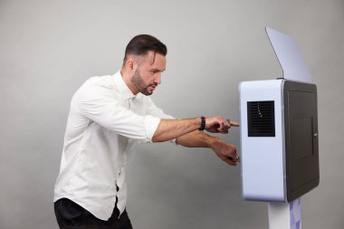 Erkek beyaz bir fotoğraf kabininin önünde poz veriyor.