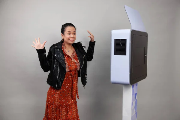 Beyaz bir fotoğraf kabininin önünde poz veren kadın.