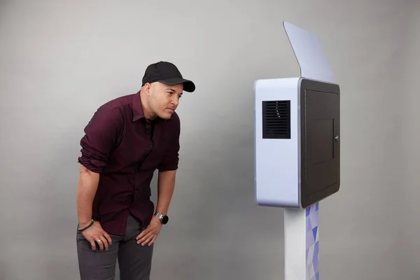 Erkek beyaz bir fotoğraf kabininin önünde poz veriyor.