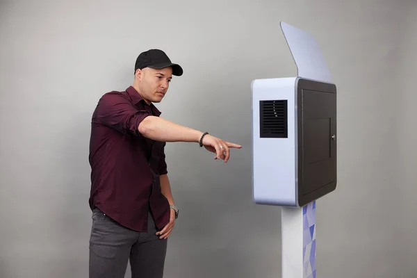 Erkek beyaz bir fotoğraf kabininin önünde poz veriyor.