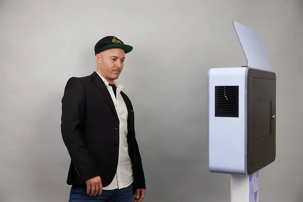 Erkek beyaz bir fotoğraf kabininin önünde poz veriyor.