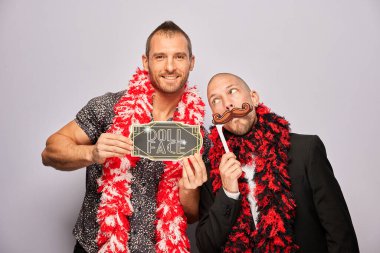 Erkek poz veriyor ve elinde aksesuar var.