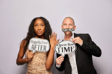 Kadın erkek poz veriyor ve elinde aksesuar var.