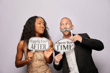 Kadın erkek poz veriyor ve elinde aksesuar var.