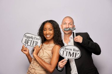 Kadın erkek poz veriyor ve elinde aksesuar var.