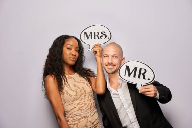 Kadın erkek poz veriyor ve elinde aksesuar var.